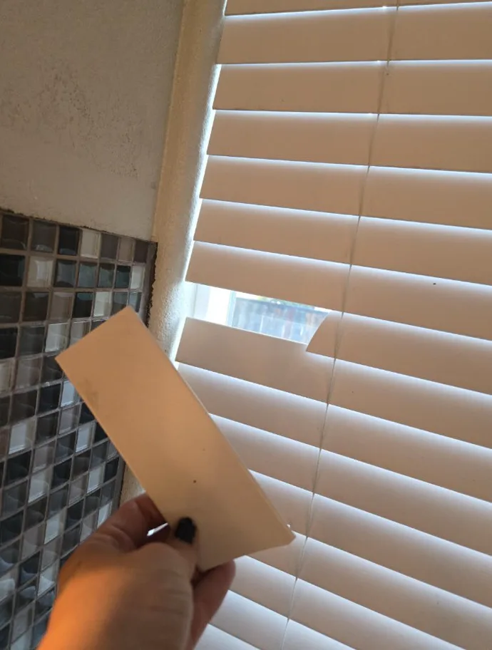 Loose window-blind slat held in front of blinds after a small household mishap